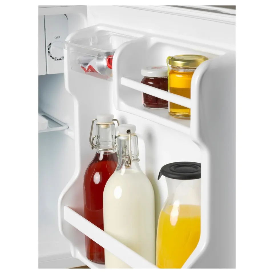 Bottles stored in refrigerator door with white shelves.