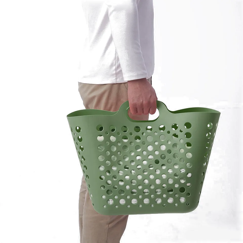 Person holding green mesh laundry basket, ideal for carrying and storing clothes.