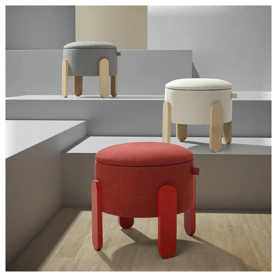 Three round FÖRLUNDA stools in red, beige, and grey with wooden legs arranged in a minimalist room.
