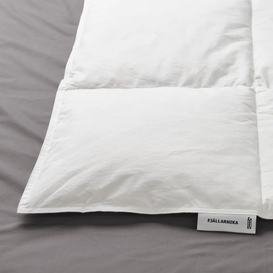 White duvet on bed, labelled FJÄLLARNIKA. Shows quality fabric and stitching.