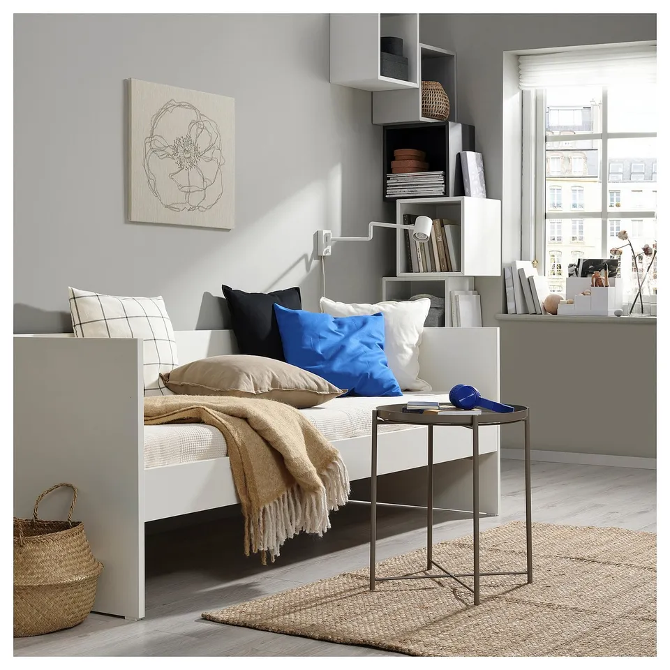 Small modern bed with shelves and pillows, a bedside table, and a rug.