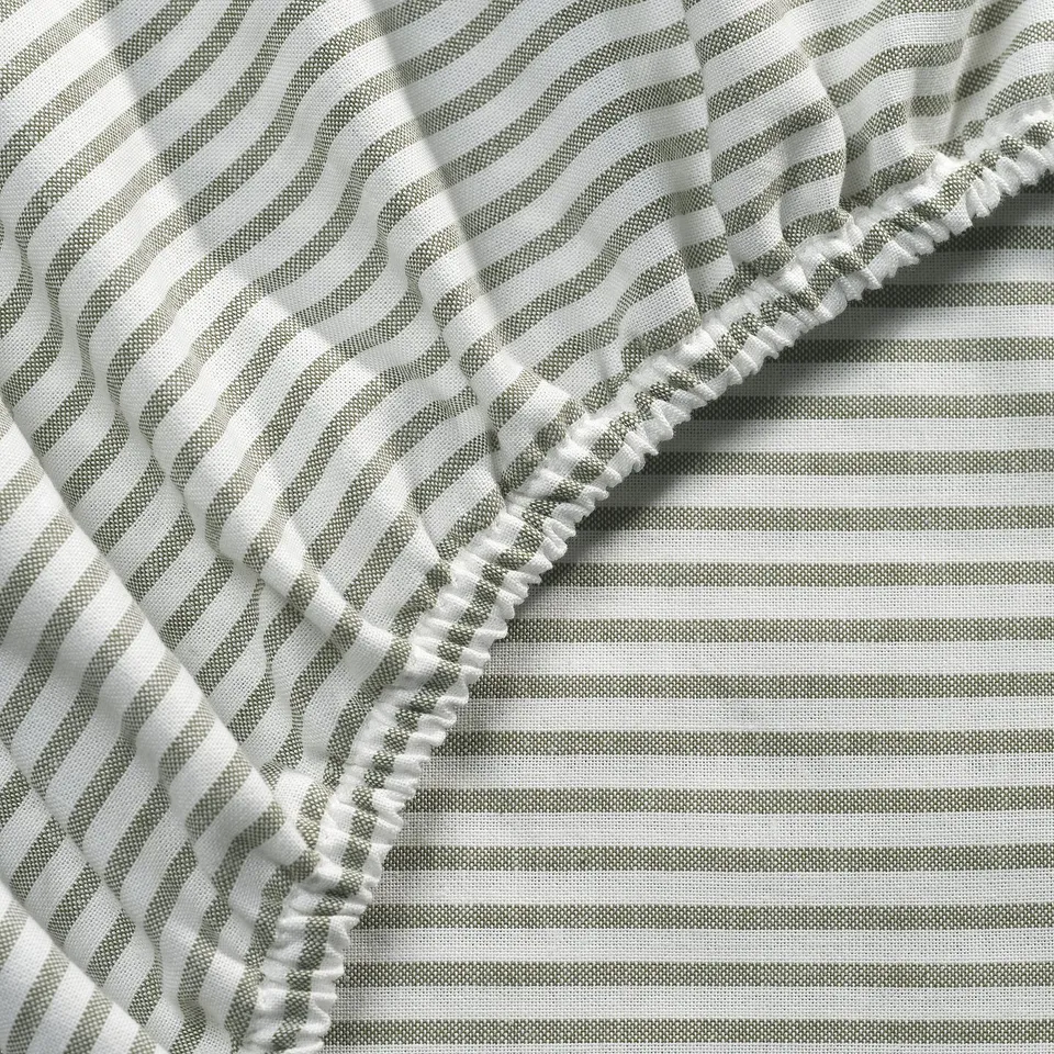 Close-up of striped cotton sheets, showcasing high-quality stitching and elastic edge detail.