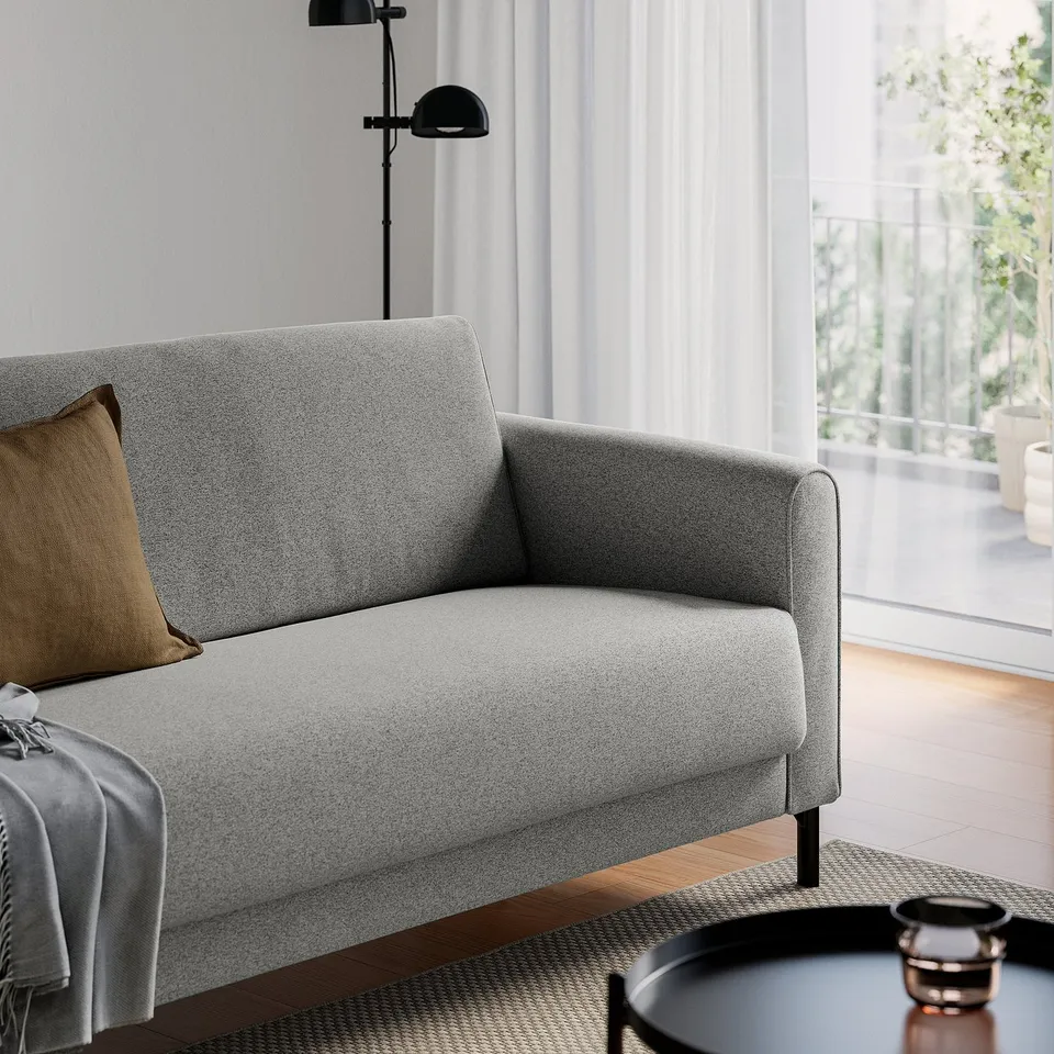 Modern living room with grey SALTMYRAN sofa, a floor lamp behind it, and a tray with drink on the rug in front.
