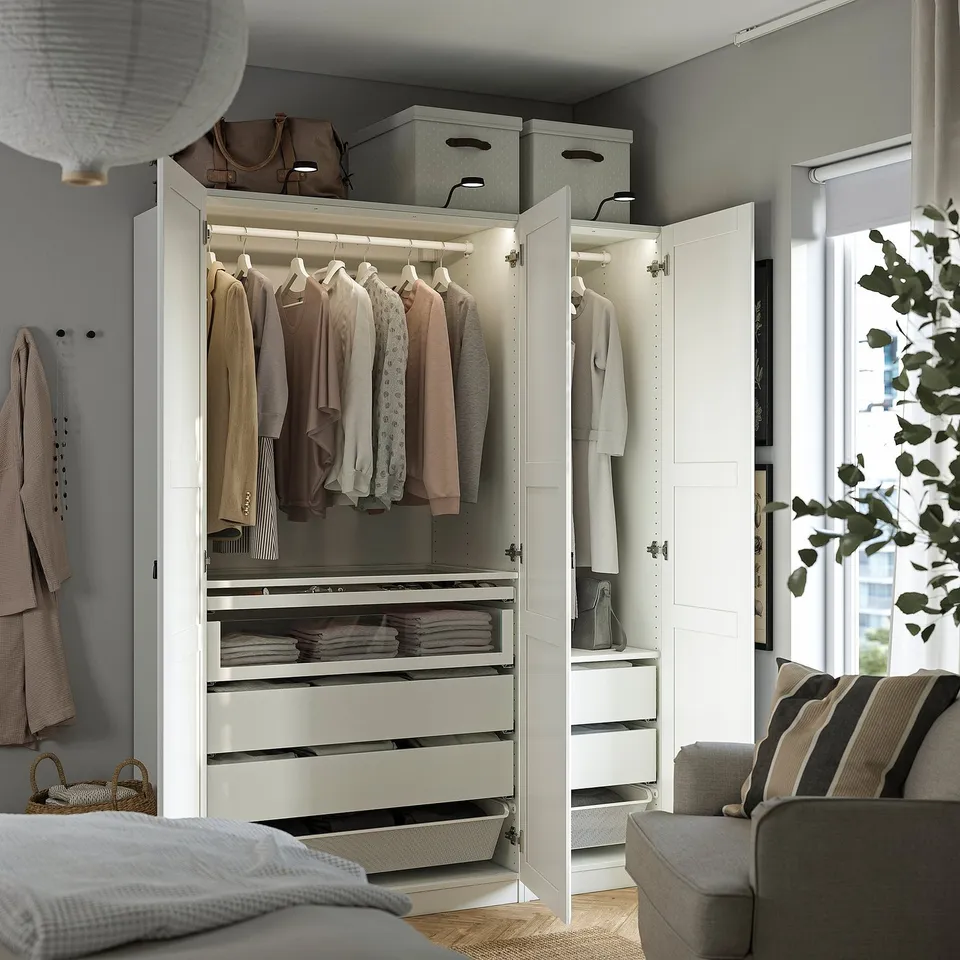 Modern bedroom with open wardrobe showcasing clothes and storage.