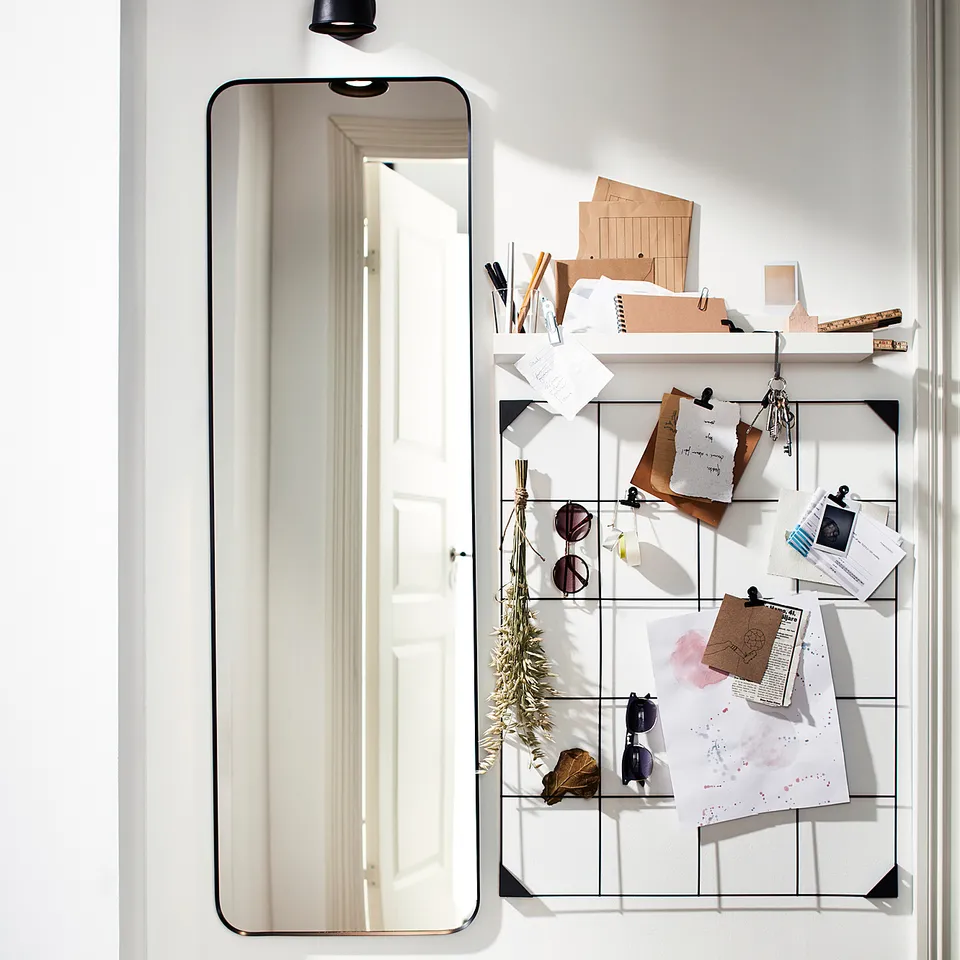 Modern hall with black-framed LINDBYN mirror, white door, wooden floor, and black lamp.