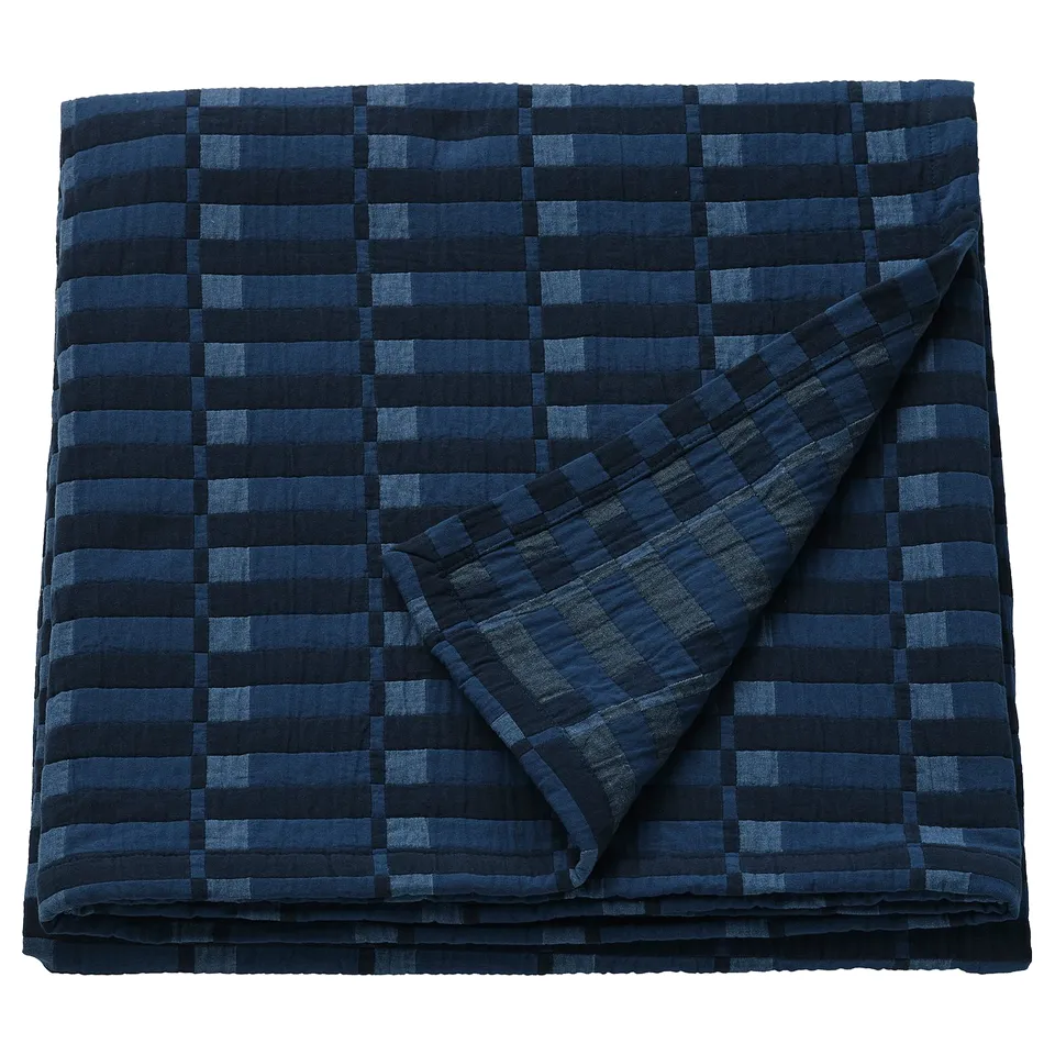 Ikea SKOGSKOVALL blue cotton blanket with dark lines folded.