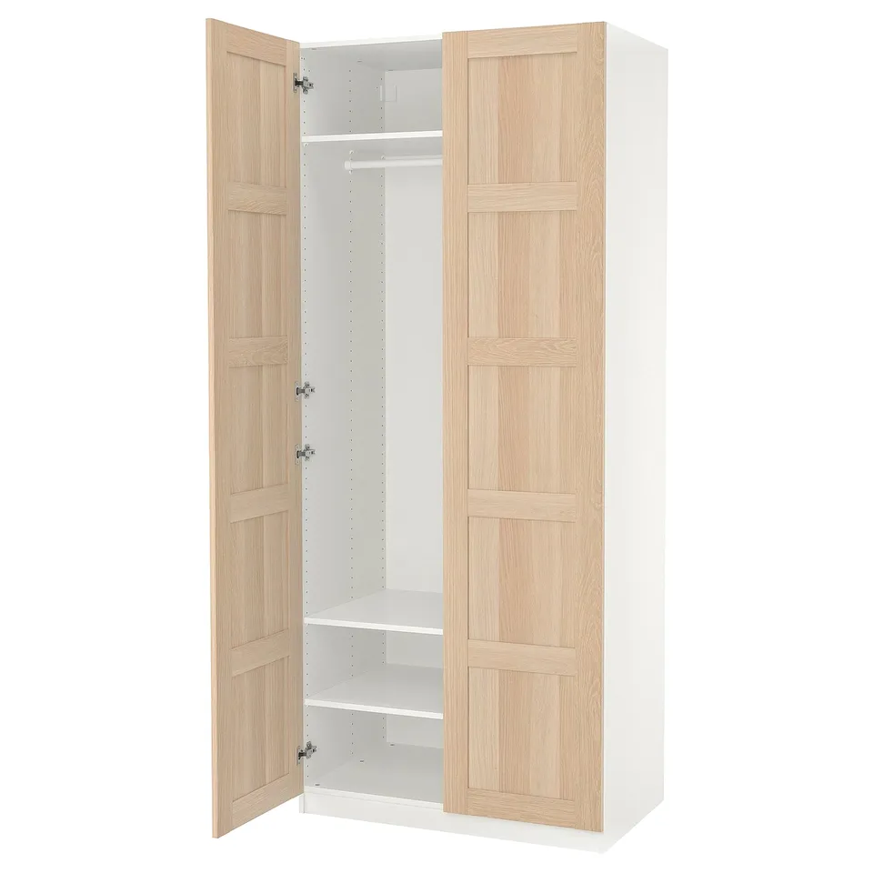 A white and light wood-colored ikea PAX wardrobe with one door open, revealing a clothes rail and shelves.