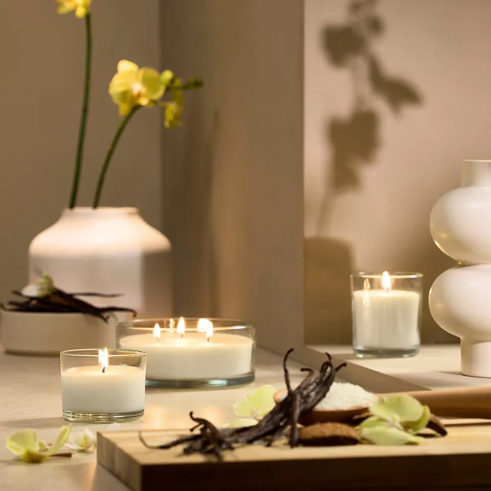 White LOTSFÅGEL candles in glass, small and large, on table with orchids.