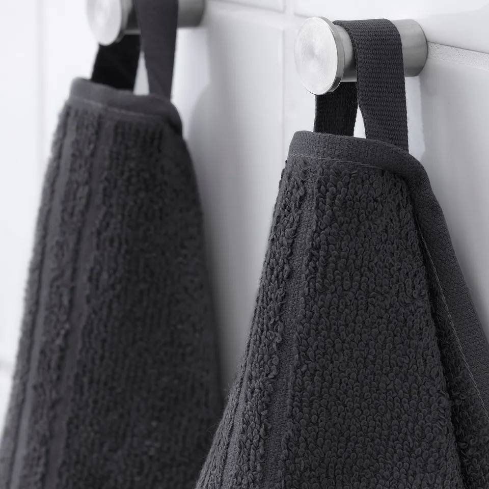 Two dark towels hang neatly from silver hooks, showcasing their soft, textured design.
