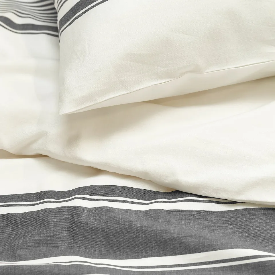 Close-up of crisp, neatly folded white sheets with black and white striped edges, showcasing high-quality cotton texture.