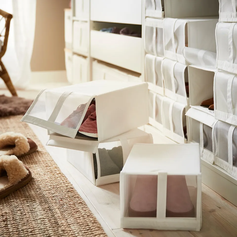 White mesh shoe boxes in closet, organised with some open, revealing shoes.