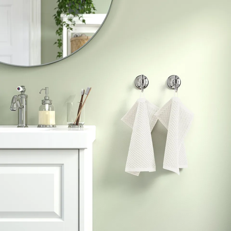Bathroom with green walls, white cabinet, sink, and two medium GULVIAL towels on chrome hooks.