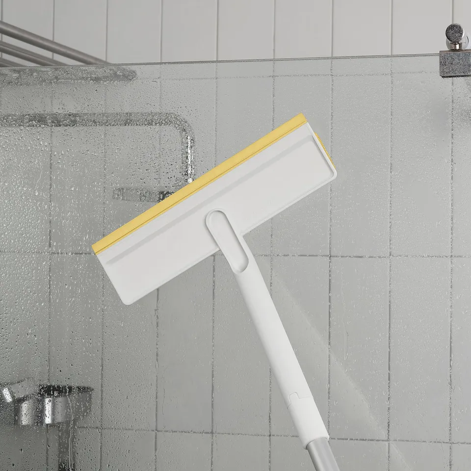 A squeegee with extendable handle cleaning a shower wall.