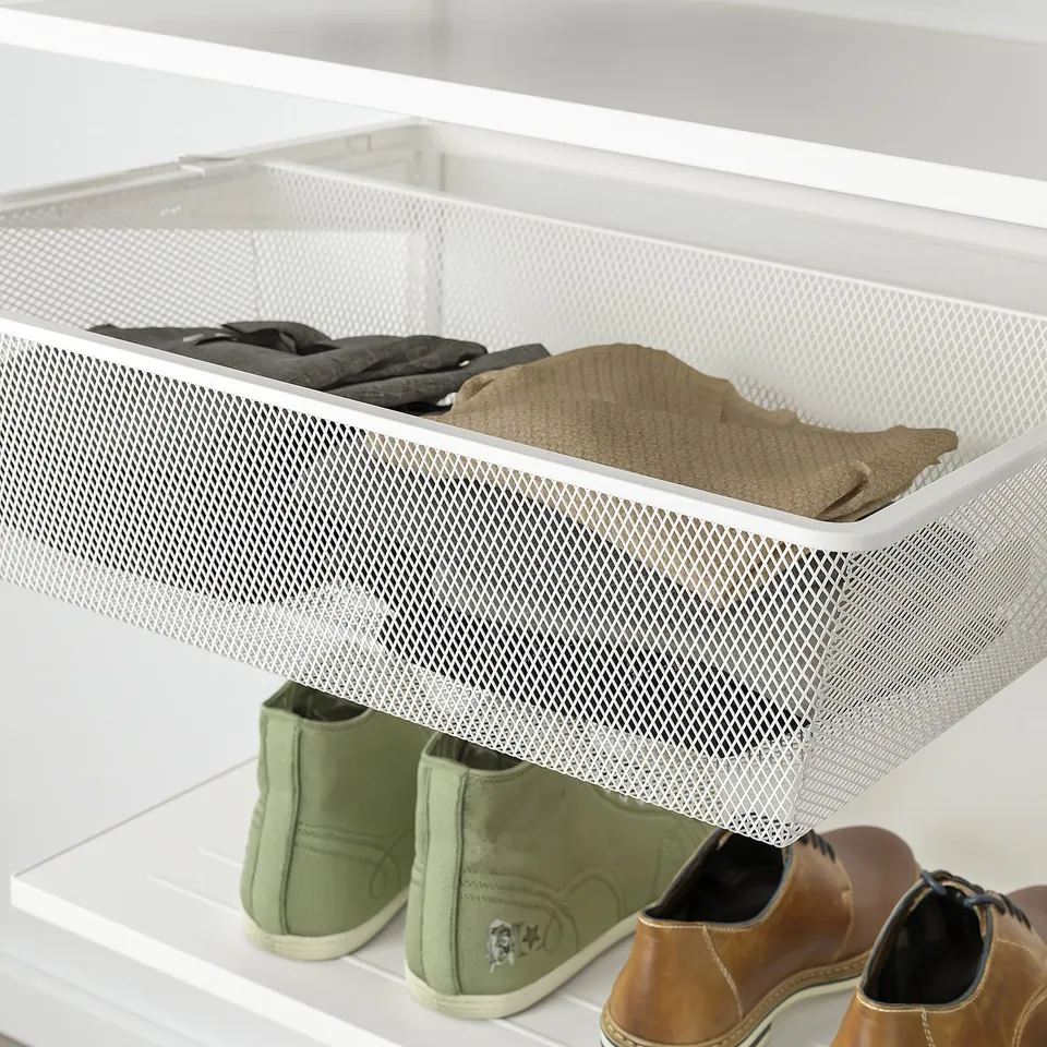 White mesh drawer filled with folded clothes, part of a wall-mounted storage system.