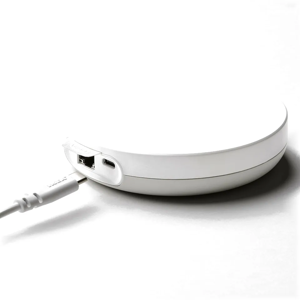 Circular white smart home hub with two usb ports and connected cable, enabling multiple device controls and integrations.