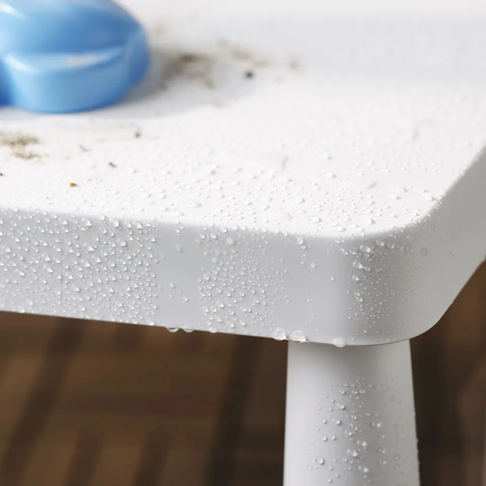 A white plastic childrens table with water droplets, easy to clean and suitable for outdoor use.