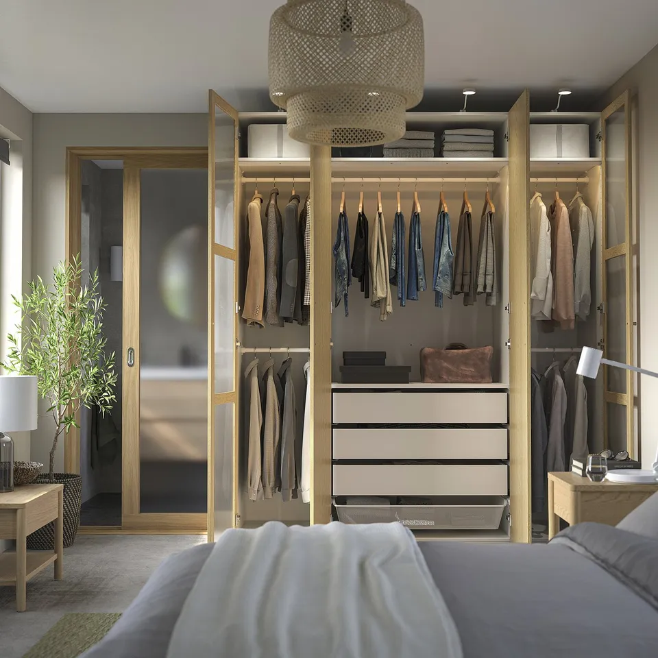 Modern bedroom with PAX wardrobe, shelves, desk, and plant.