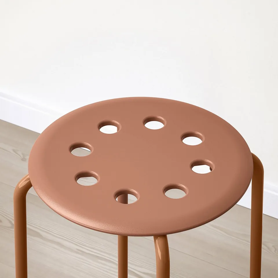 Rustic round stool with smooth legs and eight evenly spaced holes, in a minimalist setting on light wood floors and a white wall.