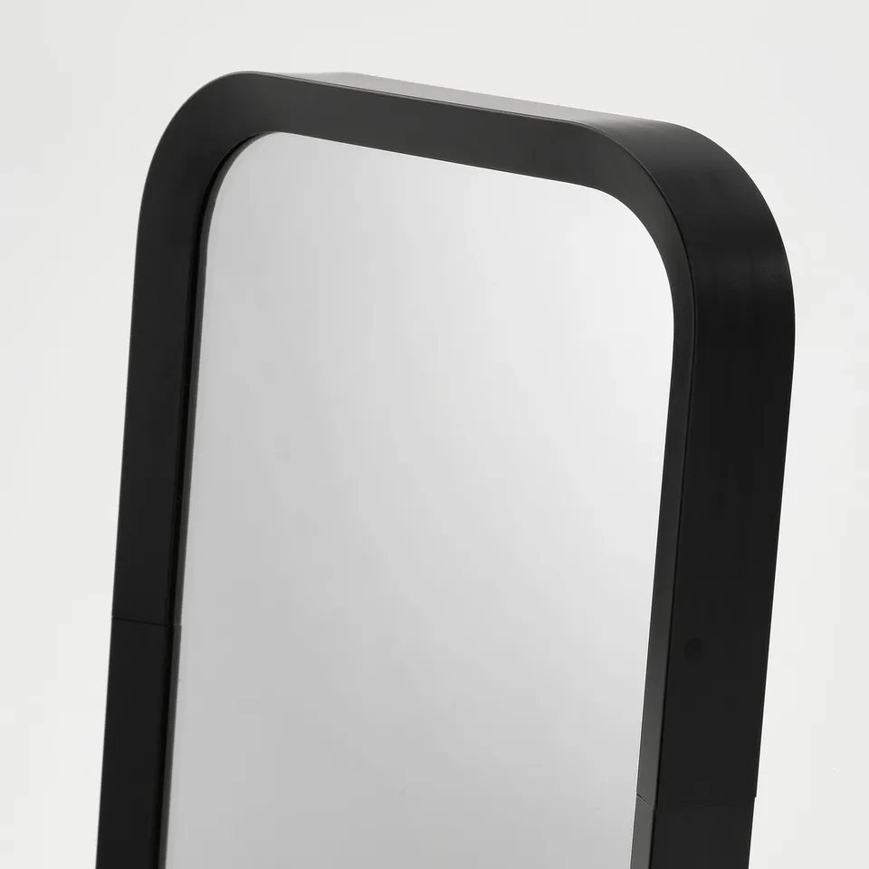 Rectangular black LINDBYN mirror with high-quality frame and magnifying side, reflecting a white background.