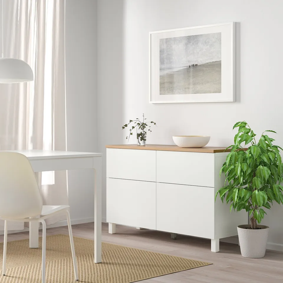 White BESTÅ sideboard with plant and picture above, by window.