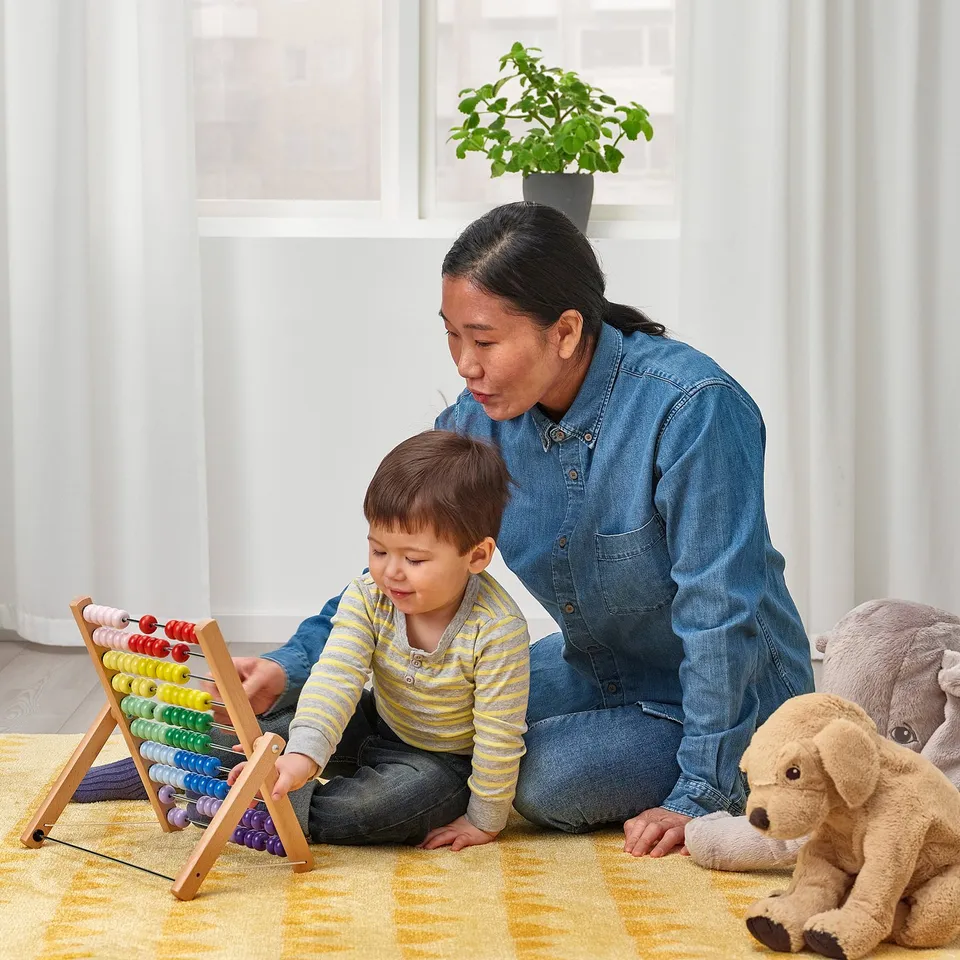 A person and child play with a colourful abacus, developing fine motor skills and learning colours and numbers.
