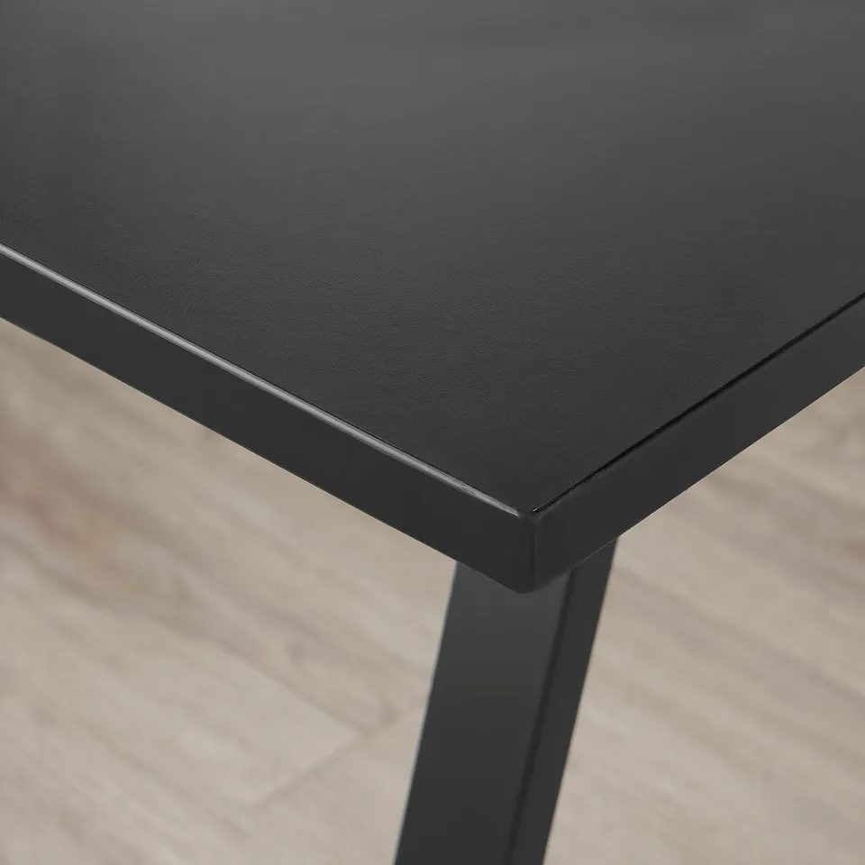 Close-up of a sleek, black UTESPELARE desk corner, showing smooth, sturdy tabletop and metal frame.