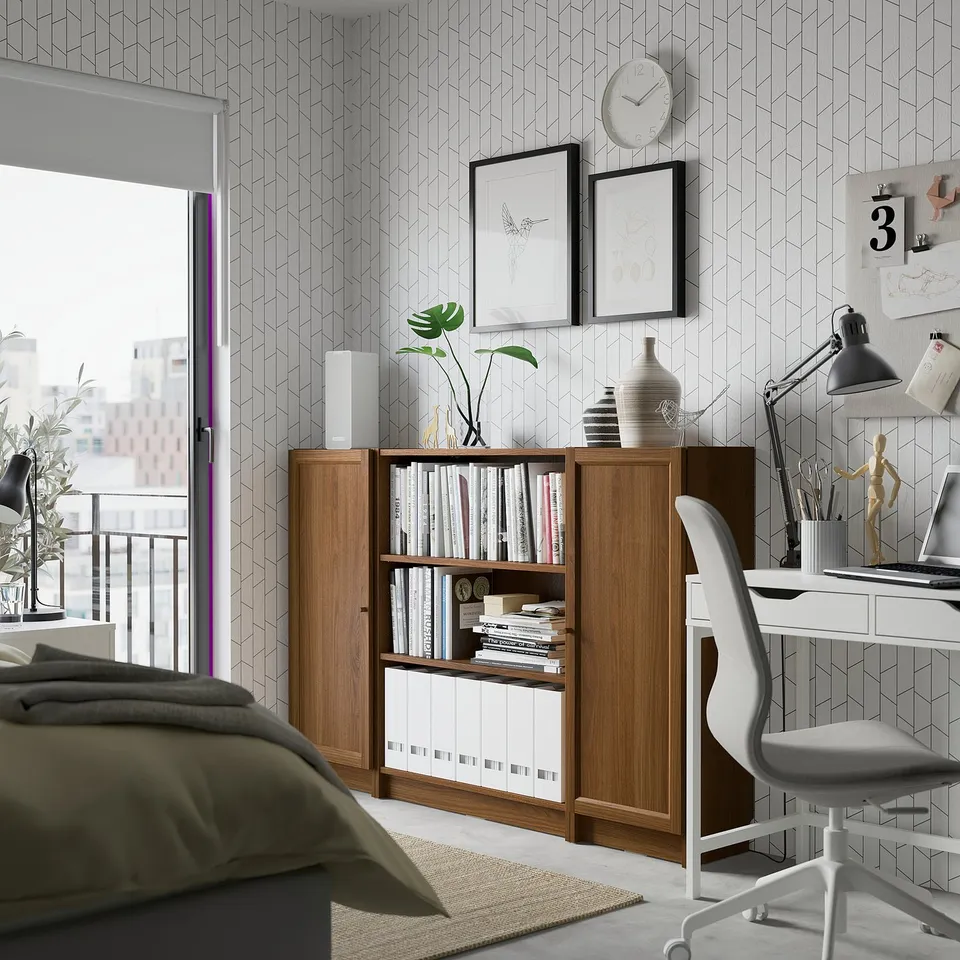 Modern home office with BILLY bookcase, white desk, and geometric-patterned wall.