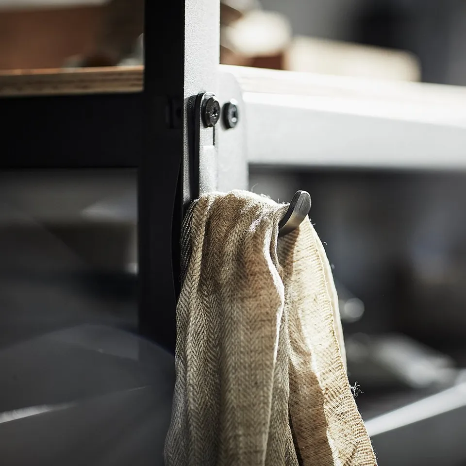 A BROR black metal hook holding a beige cloth, on a sturdy storage system.