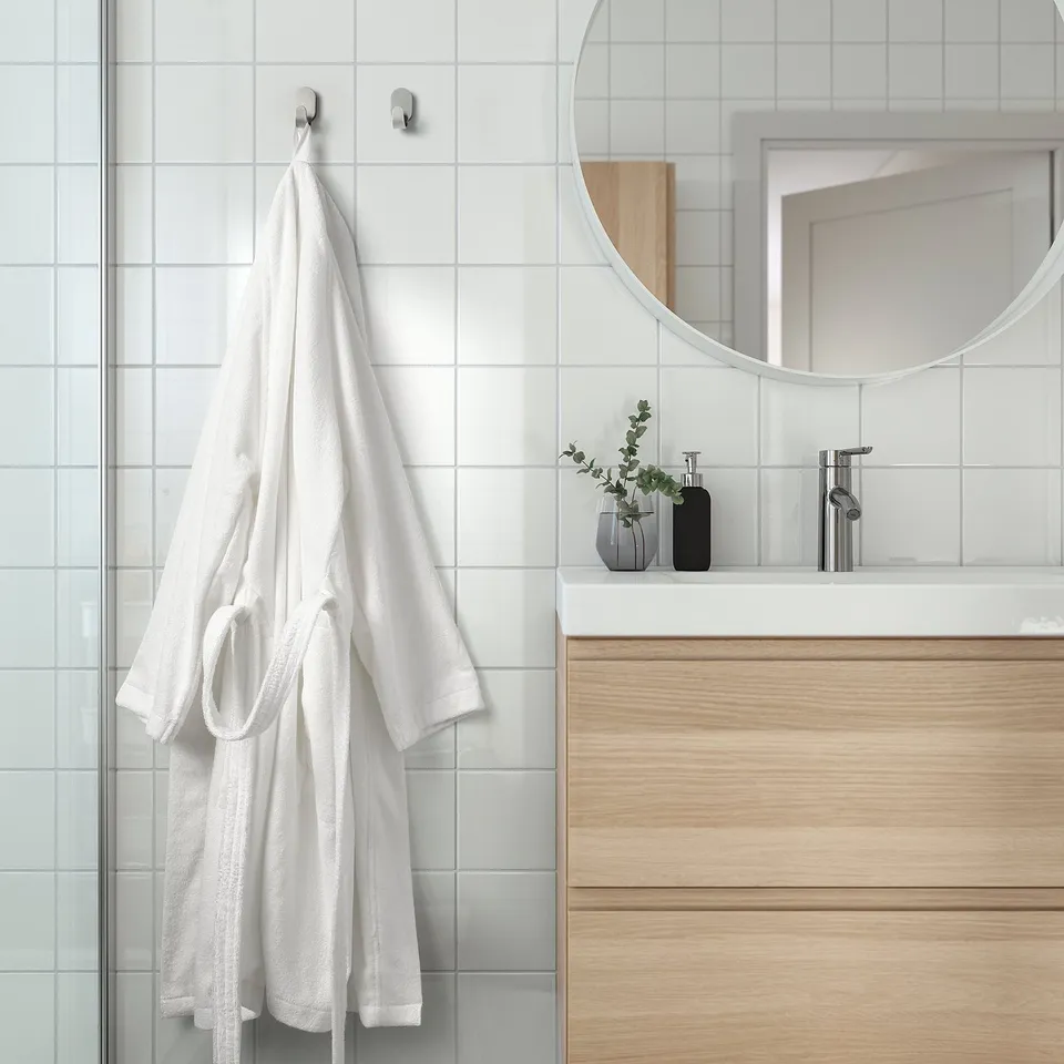 Bathroom with robe, mirror, drawers, plants, decor.