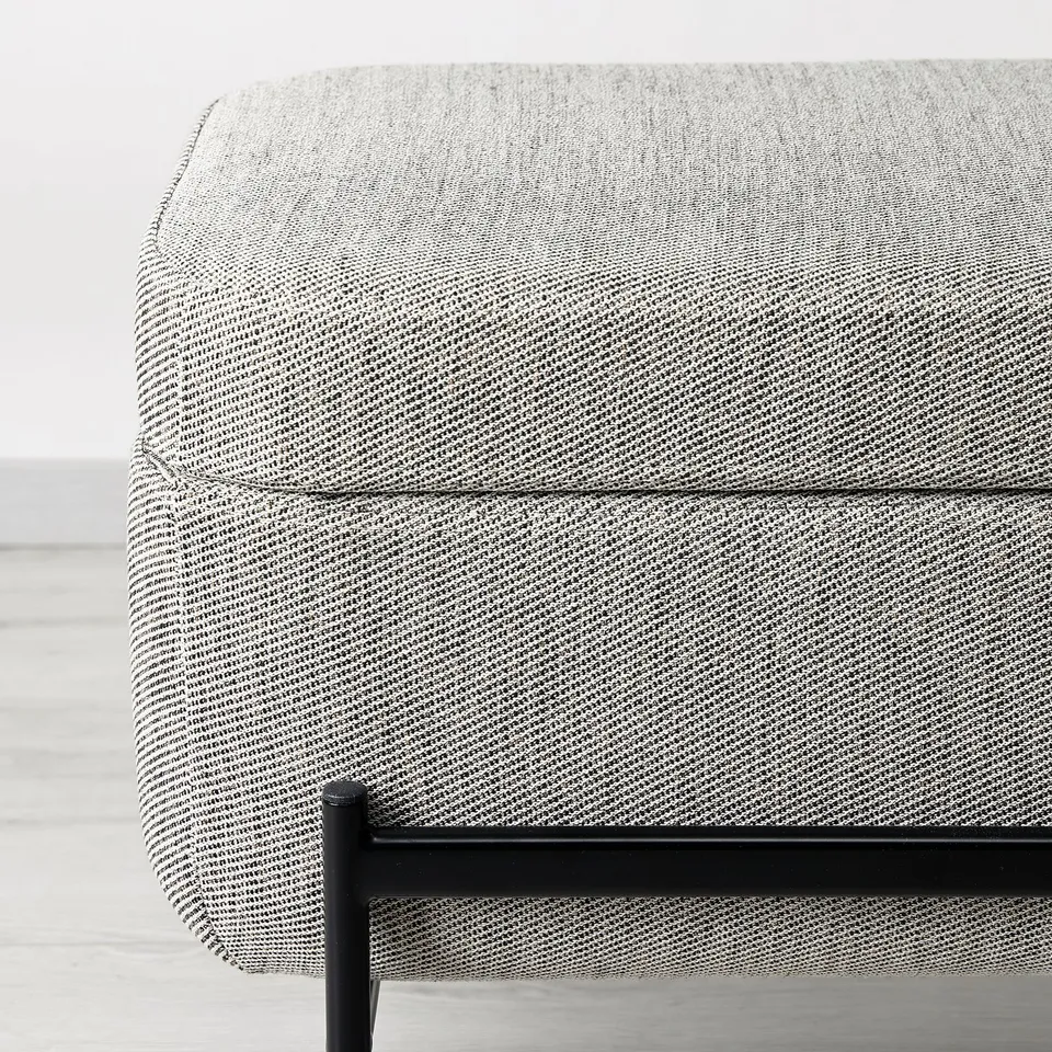 A modern, grey tweed bench with a metal frame, offering both comfort and storage.