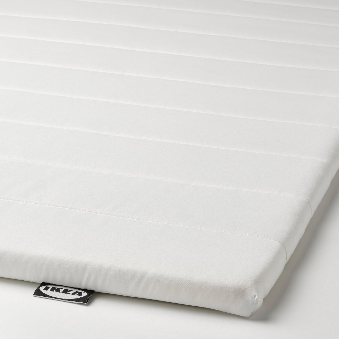 Ikea mattress topper, smooth, white with quilted pattern, showing brand tag.