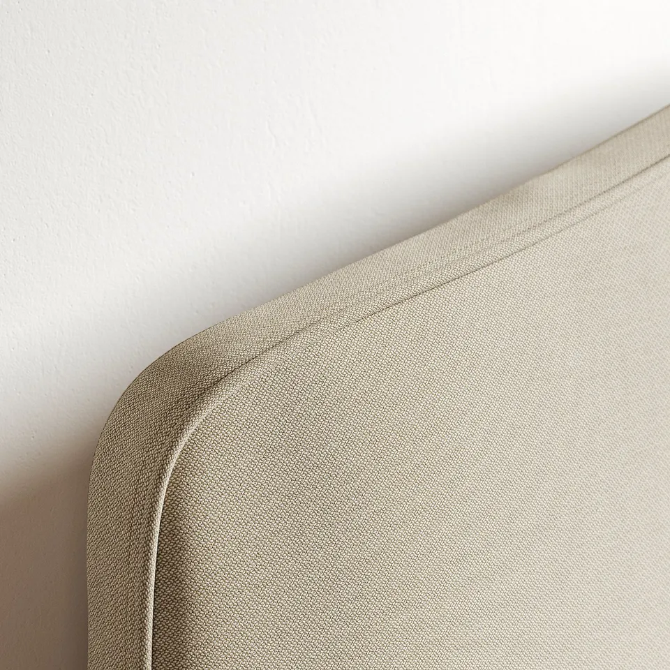 Close-up of curved headboard on upholstered bed, showing quality stitching and fabric texture.