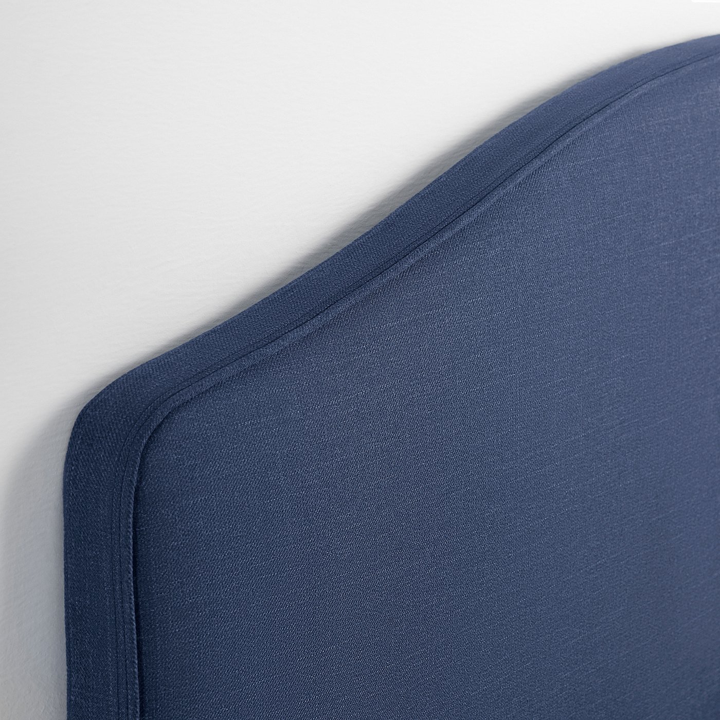 Smooth, dark blue upholstered headboard with neat stitching.