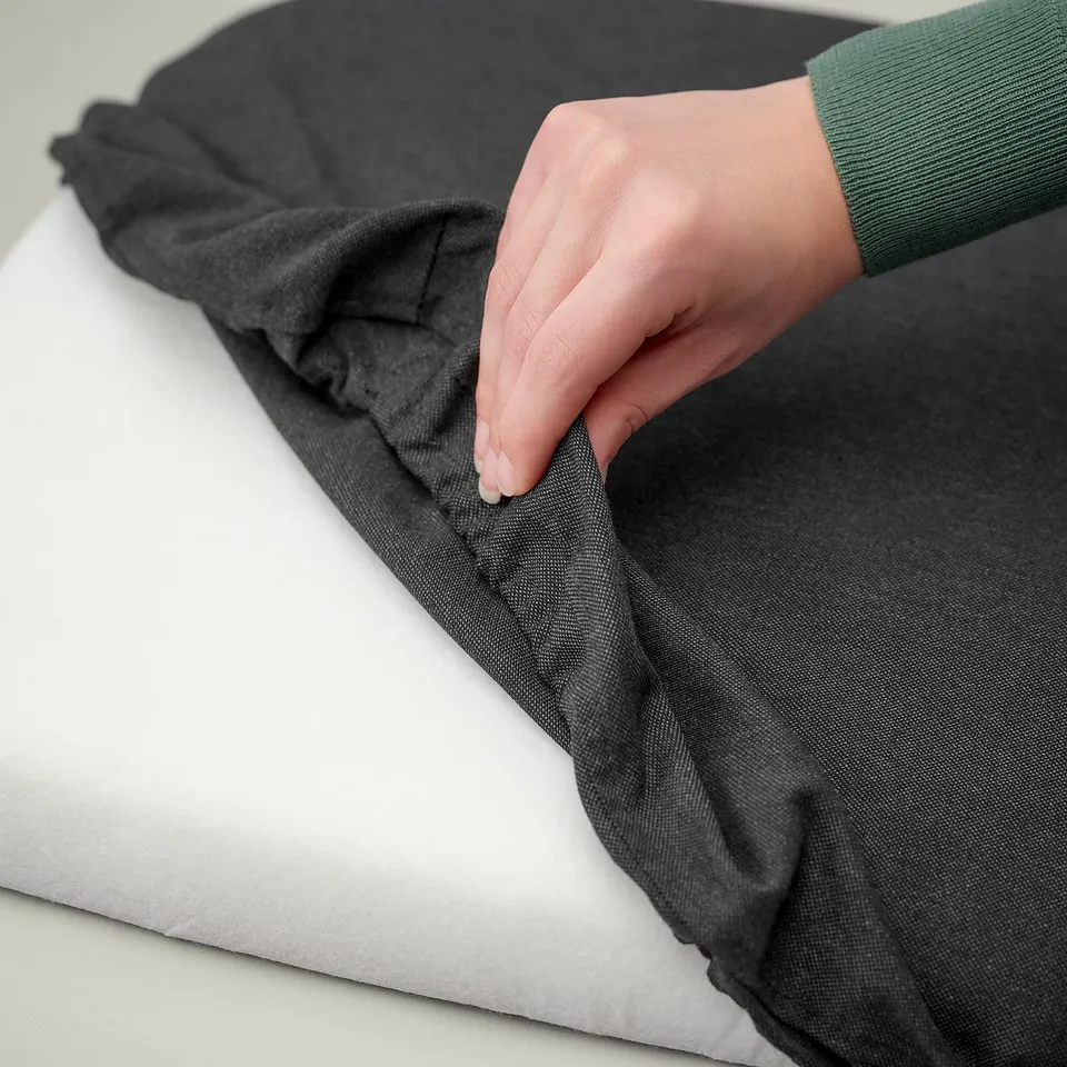 Image displays a hand touching a grey SKOGSTA fabric cover, showcasing its removable and washable feature.