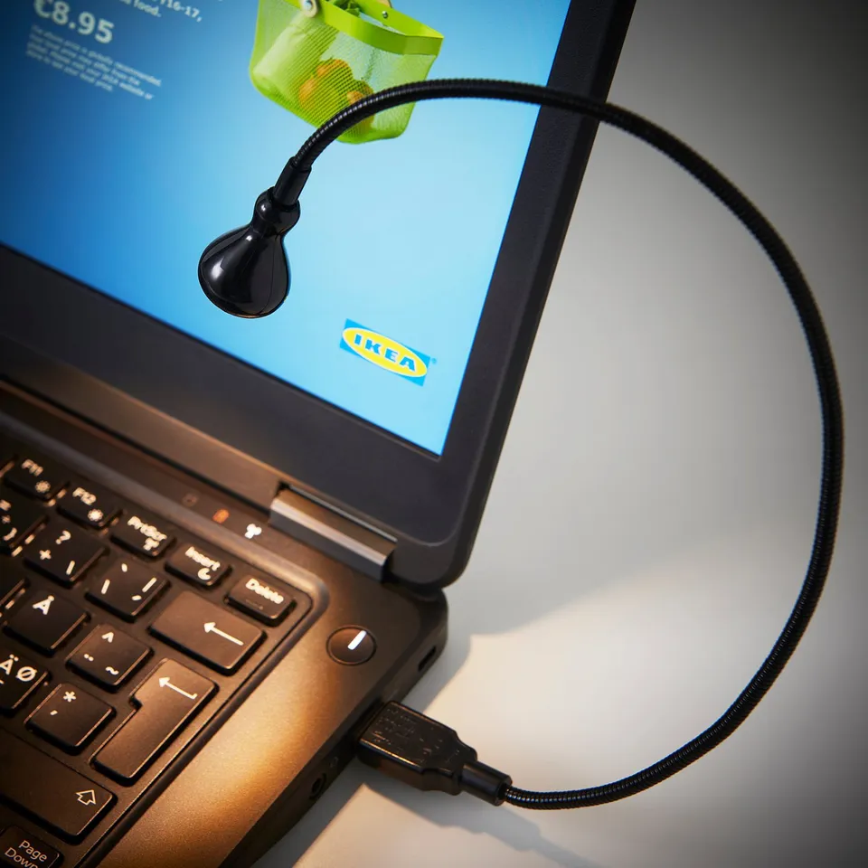 Laptop screen with a black ikea flexi-lamp attached, providing focused illumination.