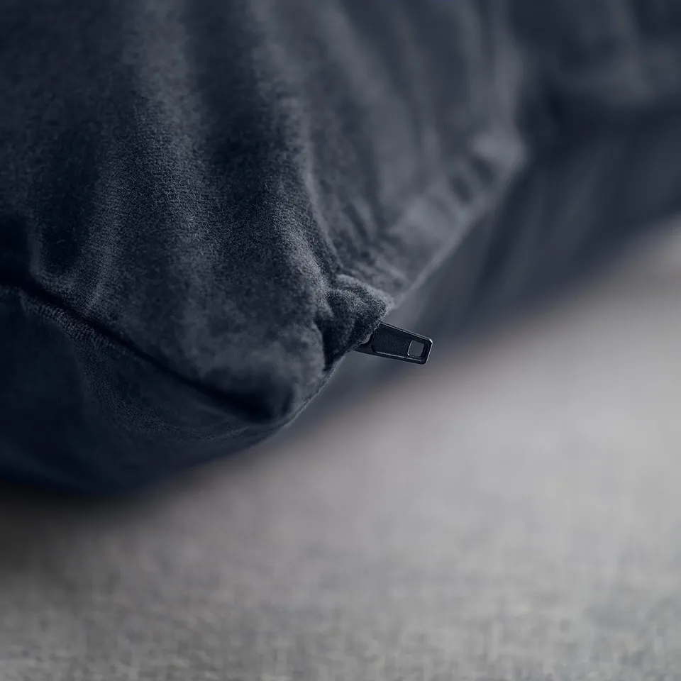 Close-up of dark blue velvet cushion cover with subtle sheen, smooth texture, and hidden zip.