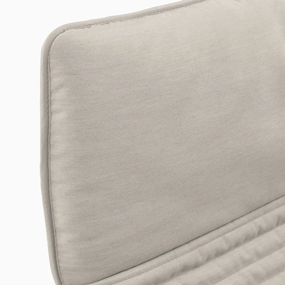 Beige upholstered armchair cushion, finely stitched, showcasing quality fabric and craftsmanship.