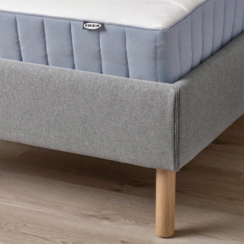 A modern bed frame with a padded headboard and wooden legs. The ikea label is visible, indicating its the TÄRNKULLEN model.