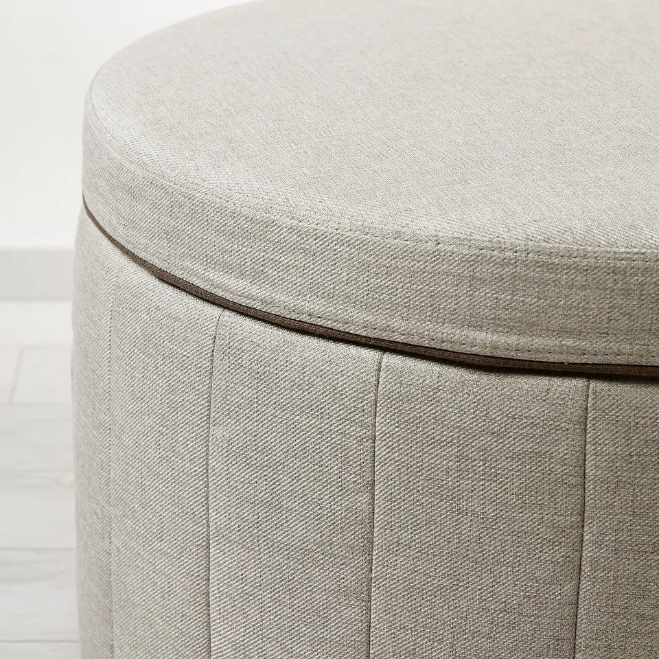 Close-up of a well-crafted, upholstered round ottoman with neat stitching and quality fabric.