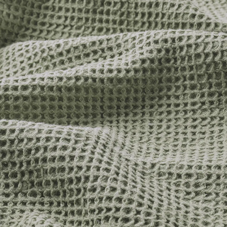 Soft, green woven towel with intricate texture, visibly plush and absorbent.