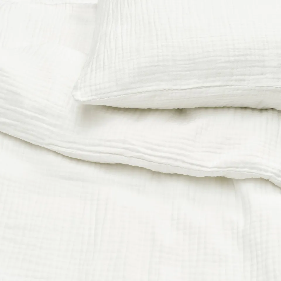 Snippet of white organic cotton duvet set showcasing soft, breathable muslin texture.