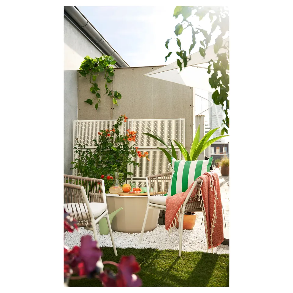 Cosy balcony setup with white SEGERÖN chairs, green cushions, and potted plants. Modern and inviting outdoor furniture arrangement.
