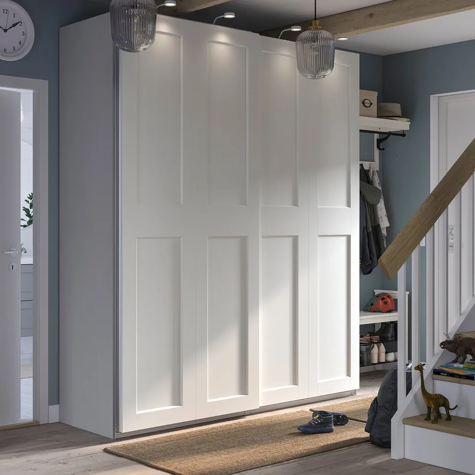 Modern entryway with white GRIMO sliding doors, blue walls, wooden floor, and stair railing. Clean lines and minimalist design.