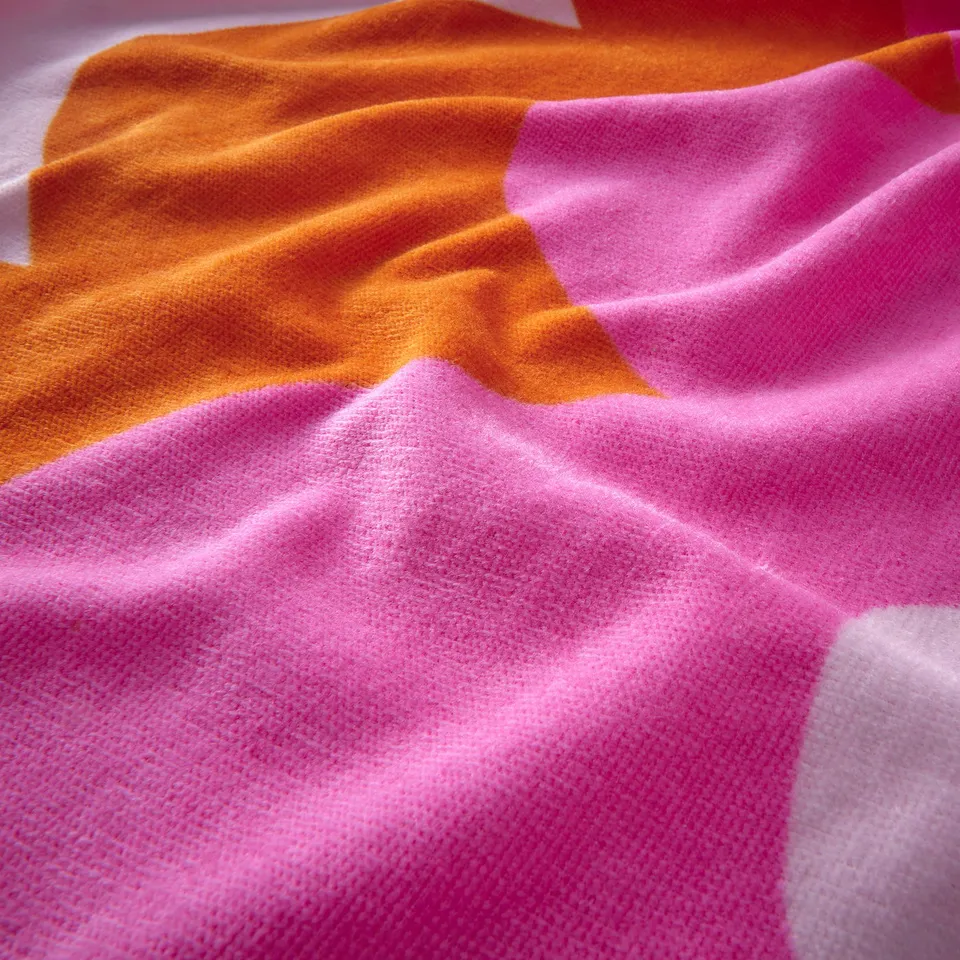 Bright orange and pink folded towel, soft textured cotton, vibrant colours.