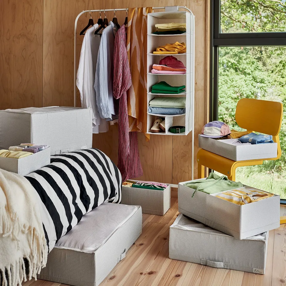 Organised bedroom with striped cushions, clothes hangers, and storage boxes.