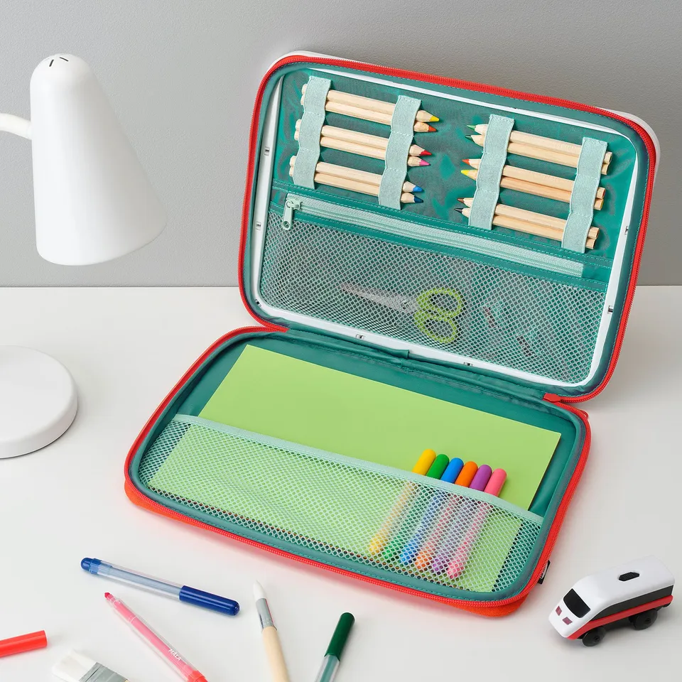 Open green and red art case displays: coloured pencils, paper, markers, and toy car, ideal for portable creativity.