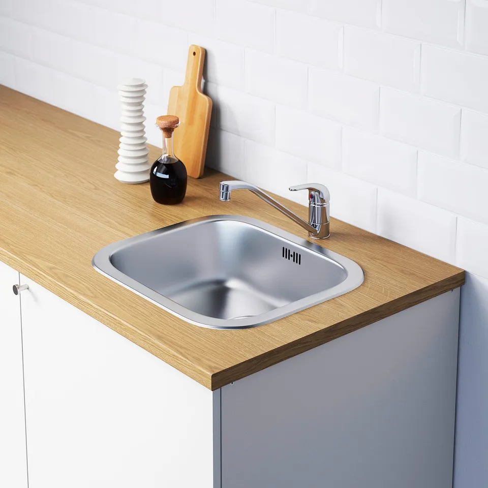 Stainless steel kitchen sink with modern chrome tap, set in wooden countertop with integrated storage and accessories.