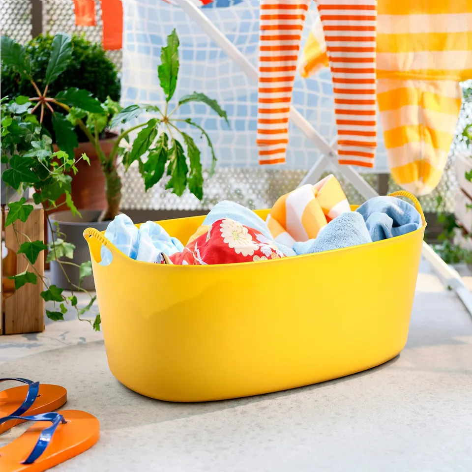 Yellow TORKIS basket with colourful towels. Lightweight plastic, ideal for laundry.