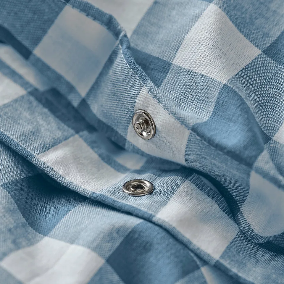 Close-up of blue-white chequered duvet cover with metal snap closure.
