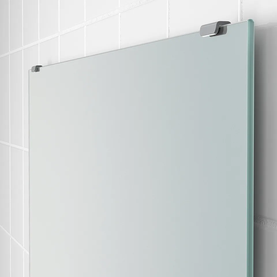 A large, modern mirror mounted on a tiled wall, showcasing its sleek frame and reflective surface.